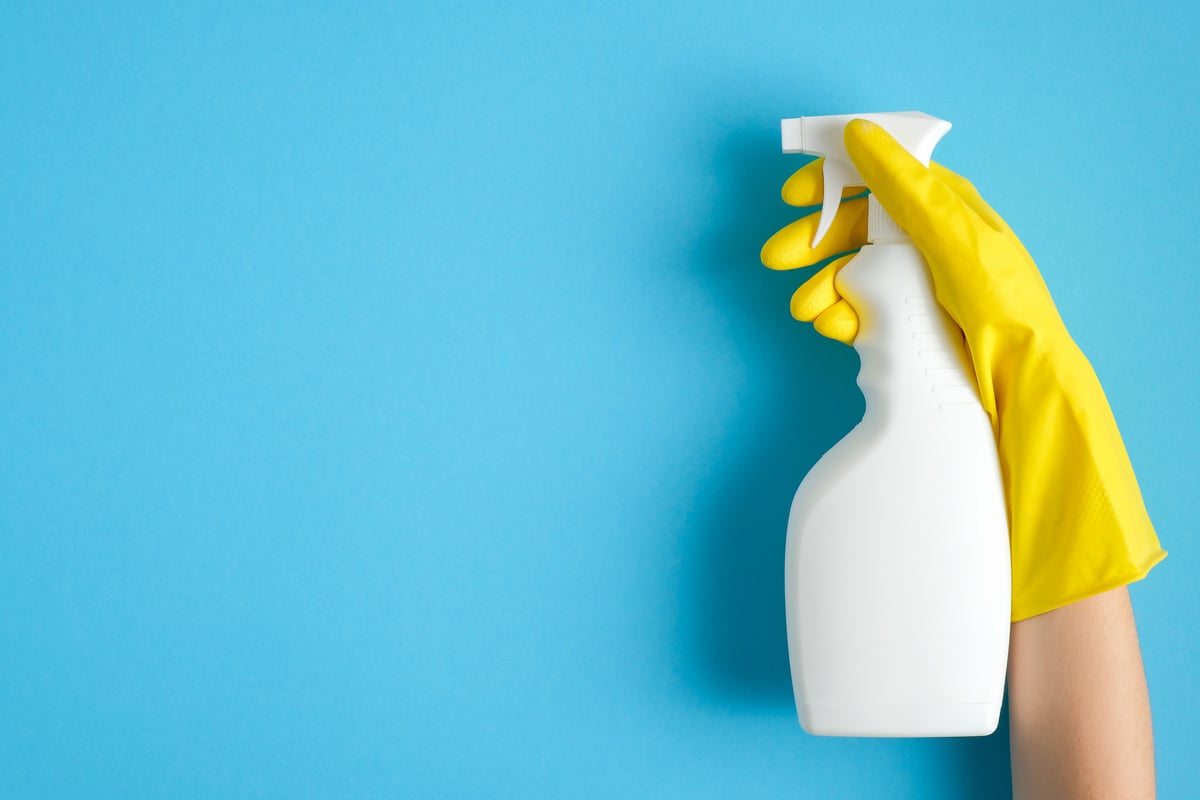 Hand in a Yellow Rubber Glove Holds Cleaner Spray Bottle 