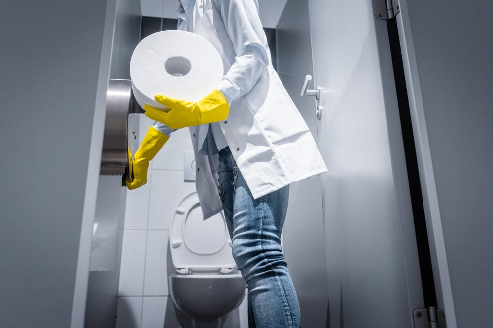 Janitor Woman Changing Paper in Public Toilet